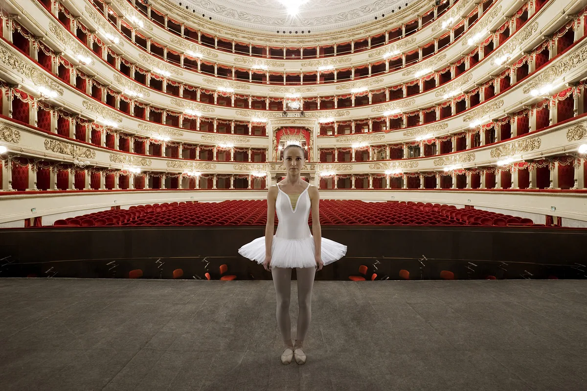 Giovane ballerina in tutù bianco al centro del palco del Teatro alla Scala, palchi rossi e dorati alle spalle — Filippo Piantanida e Roberto Prosdocimo