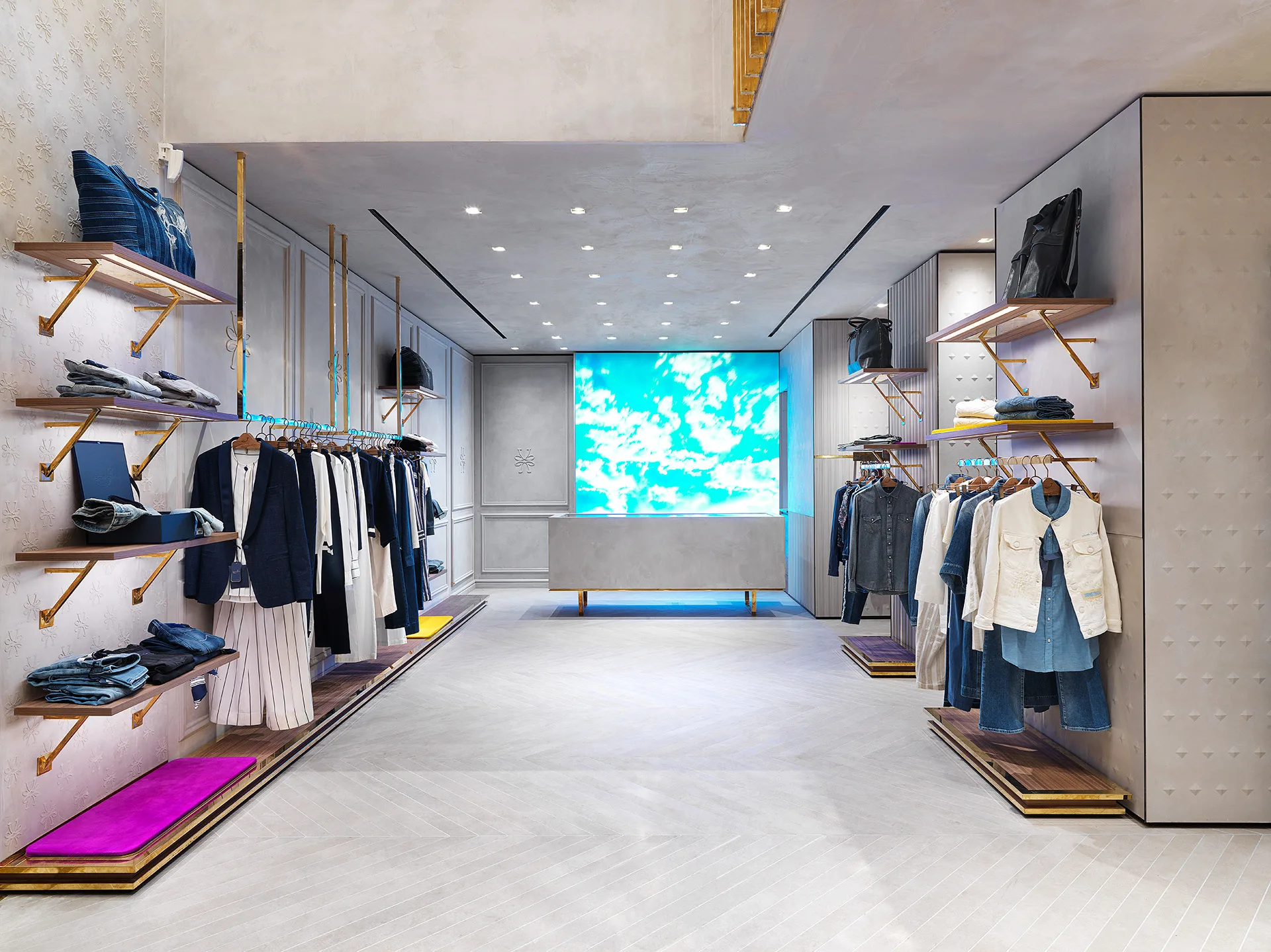 Jacob Cohën Milan store room with denim rails, brass shelves and a large LED screen showing a blue sky at the back — photo Filippo Piantanida Studio