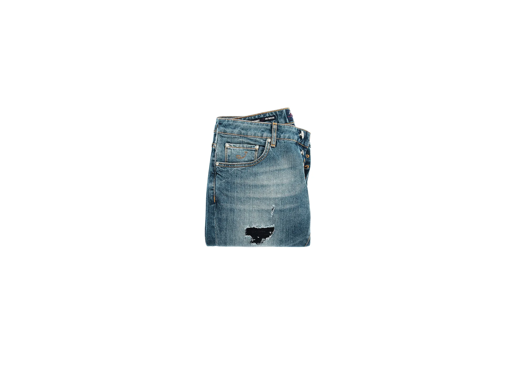 Folded Jacob Cohen jeans with a patched tear and light wash on a white background — product still life, Filippo Piantanida Studio
