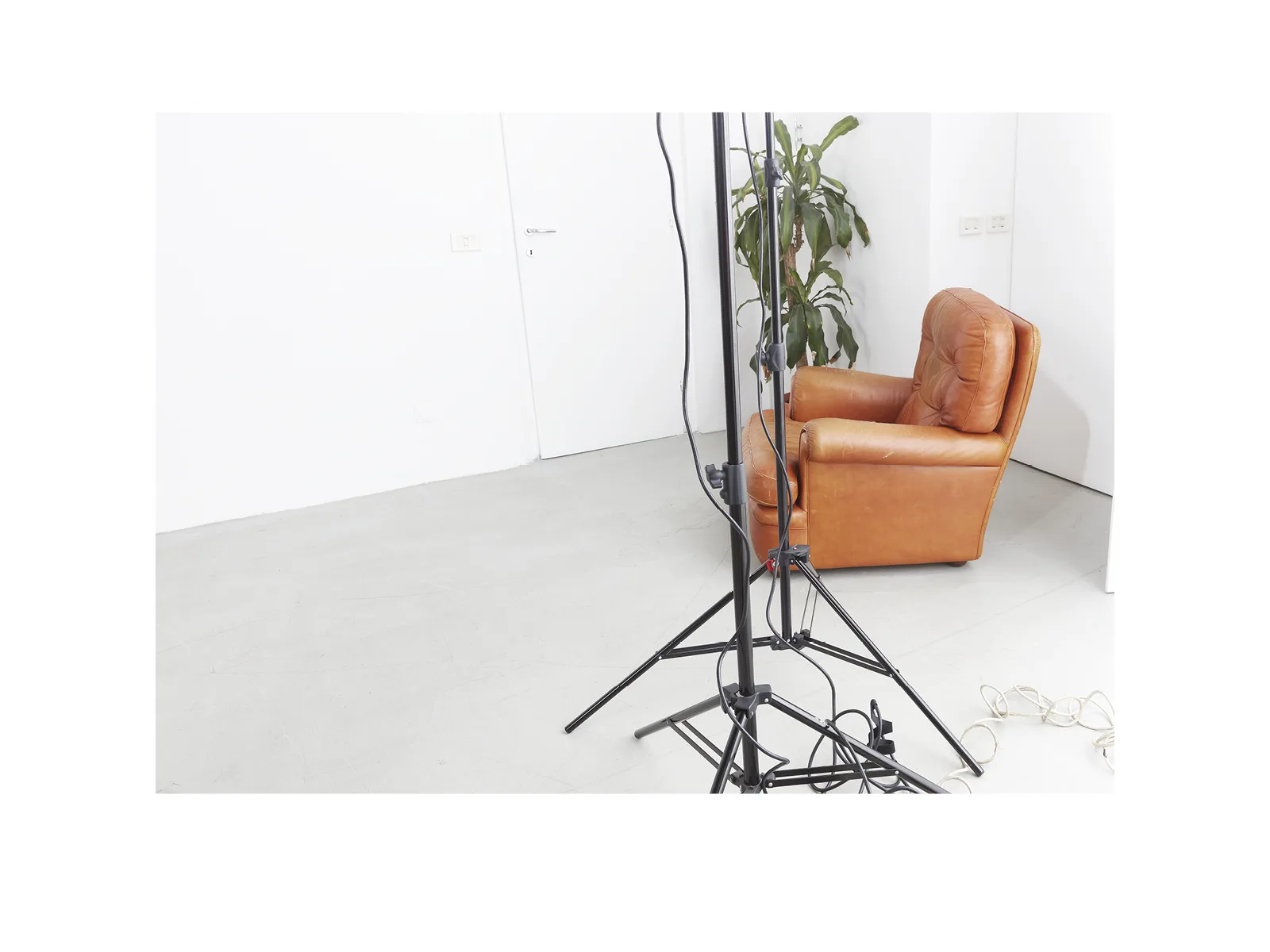 Backstage of a photo set for catalogues: orange leather armchair and lighting stands in a minimal environment