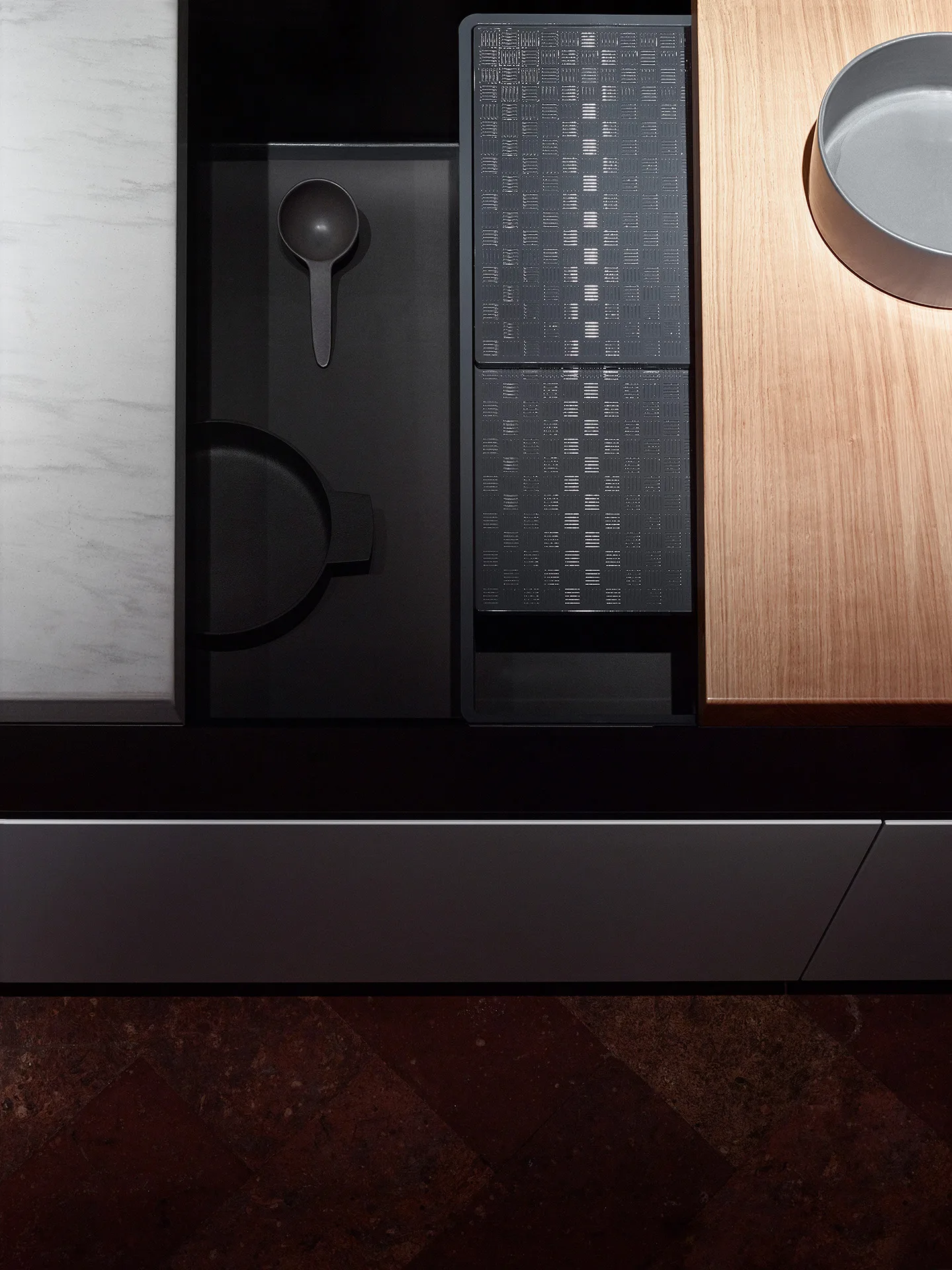 Top view of a Bulthaup drawer with black ladle and container and a perforated board, amid marble, oak and stone — Wallpaper editorial, Filippo Piantanida Studio
